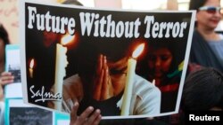 A boy holds a poster during a civil society protest rally against terrorism in Lahore, January 16, 2015.