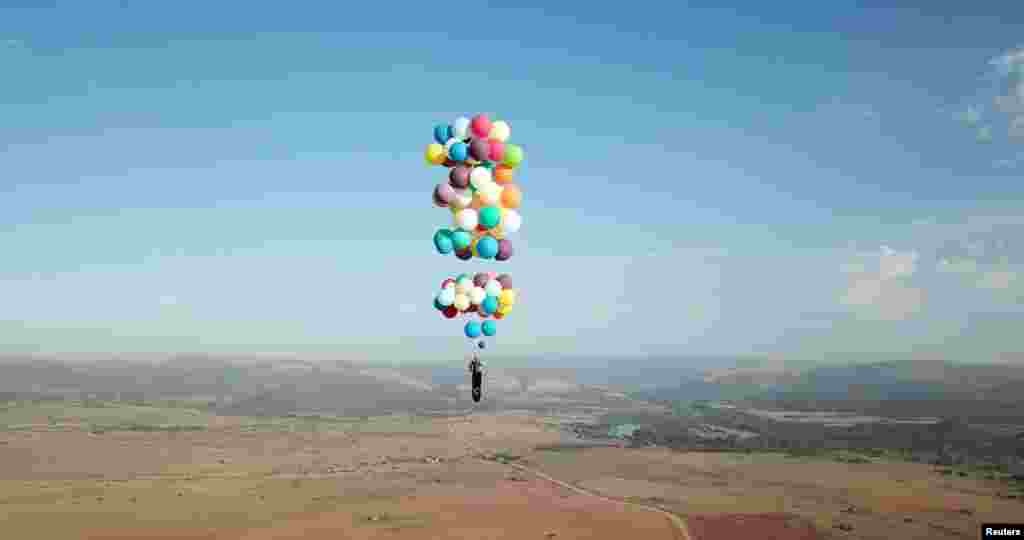 Tom Morgan, from Bristol-based company The Adventurists, flies in a chair tied to large party balloons near Johannesburg, South Africa.