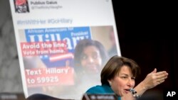 Senator AS, Amy Klobuchar, di depan poster iklan online yang menampilkan keterlibatan perusahaan teknologi Rusia dalam kegiatan pemilu AS dalam laporan di Gedung Capitol, 31 Oktober 2017. (Foto: dok). 