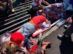 Activist Walter Ritte, left, and others lay chained to a cattle grate blocking a road at the base of Hawaii's tallest mountain, July 15, 2019, in Mauna Kea, Hawaii.
