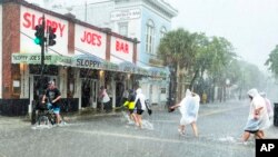 Los turistas no se dejan intimidar por la tormenta tropical Elsa a su paso cerca de Cayo Hueso el 6 de julio de 2021 y acuden bajo la lluvia y el viento al famoso restaurante Sloppy Joe's.