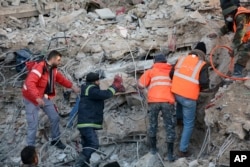 Petugas pertahanan sipil mencari melalui puing-puing bangunan yang runtuh di kota pesisir Latakia, Suriah, Rabu, 8 Februari 2023. (Foto: SANA via AP)