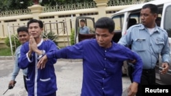 Born Samnang (2nd L) and Sok Sam Oeun (2nd R) are escorted by police officers at the Supreme Court in central Phnom Penh, Sept. 25, 2013.
