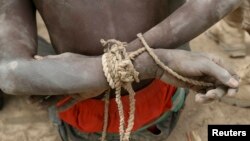 FILE - A prisoner, suspected of being a member of insurgent group Boko Haram, sits with his arms tied behind his back in the field base of Chadian soldiers in Gambaru, Nigeria.