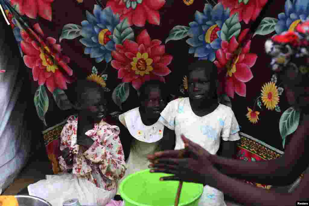 South Sudanese girls sit by a tent in a camp for displaced persons in the United Nations Mission in South Sudan (UNMISS) compound in Tongping in Juba, February 19, 2014.