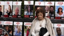 A woman pauses near posters of hostages held by Hamas in the Gaza Strip, in Tel Aviv, Israel, as Israel's security Cabinet convenes on Jan. 17, 2025.