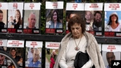 A woman pauses near posters of hostages held by Hamas in the Gaza Strip, in Tel Aviv, Israel, as Israel's security Cabinet convenes on Jan. 17, 2025.