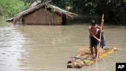 Flood affected boys move on a banana raft near partially submerged houses in Morigaon district east of Gauhati, Assam, India, Tuesday, Aug. 15, 2017.