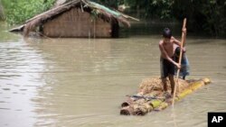15일 인도 아삼주 모라가온 지역이 홍수로 침수된 가운데 마을 주민이 바나나 나무로 만든 뗏목을 타고 이동하고 있다.
