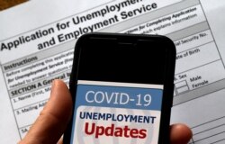 FILE - In this illustration photo taken May 08, 2020, a COVID-19 Unemployment Assistance Updates logo is displayed on a smartphone against the backdrop of an application for unemployment benefits, in Arlington, Virginia.