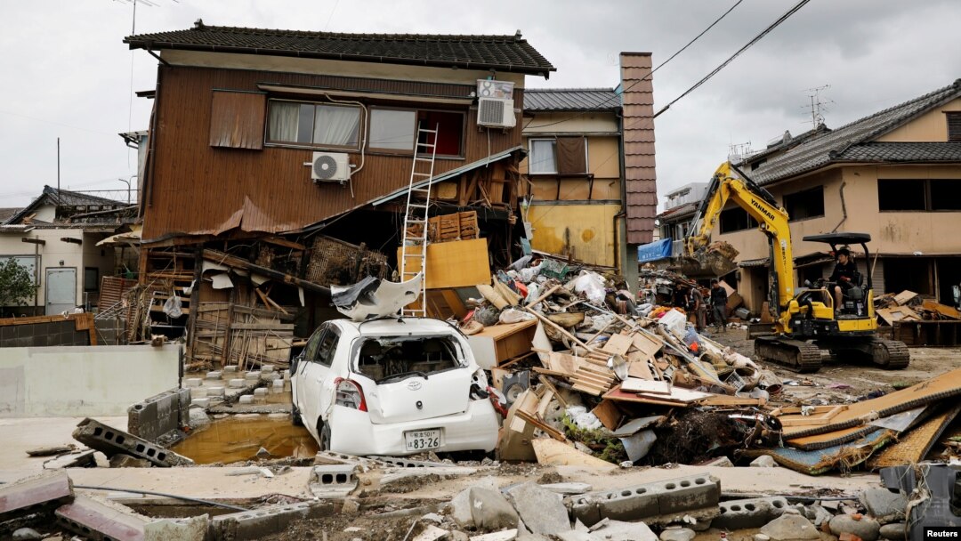 Ekskavator membersihkan puing-puing di sebelah rumah yang hancur akibat banjir yang dipicu hujan lebat di Hitoyoshi, Prefektur Kumamoto, Jepang barat daya, 8 Juli 2020.