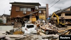 Ekskavator membersihkan puing-puing di sebelah rumah yang hancur akibat banjir yang dipicu hujan lebat di Hitoyoshi, Prefektur Kumamoto, Jepang barat daya, 8 Juli 2020.