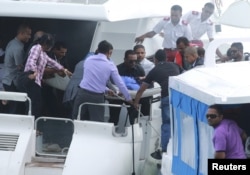 FILE - Officials carry an injured woman off the speed boat of Maldives President Abdulla Yameen Abdul Gayoom (not pictured) after an explosion onboard, in Male, Maldives, Sept. 28, 2015.