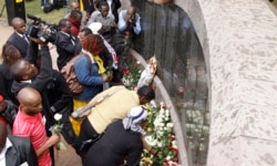FILE - People lay flowers at the U.S. Embassy bombing memorial site in Nairobi, Kenya, Aug. 7, 2013, to mark the 15-year anniversary of the 1998 embassy bombing.