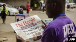 Un Zimbabwéen lit la Une du journal The Herald sur la crise au Zimbabwe, le 15 novembre 2017. AFP PHOTO /