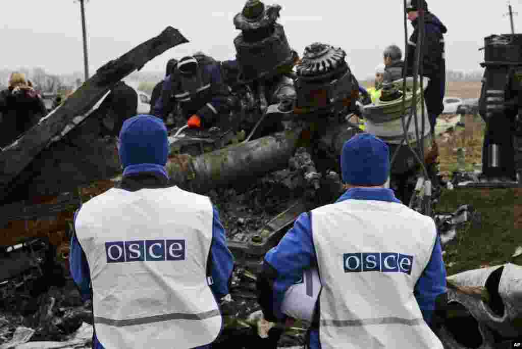 OSCE members watch as recovery workers in rebel-controlled eastern Ukraine load debris from the crash site of Malaysia Airlines Flight 17, in Hrabove, Ukraine, Nov. 16, 2014.