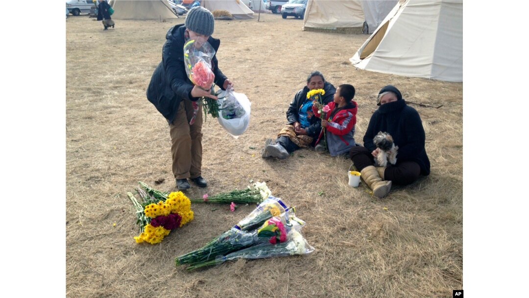 An opponent of the Dakota Access oil pipeline passes out flowers at the main protest camp near Cannon Ball, N.D., Nov. 15, 2016.