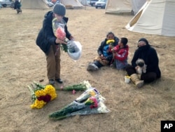 An opponent of the Dakota Access oil pipeline passes out flowers at the main protest camp near Cannon Ball, N.D., Nov. 15, 2016.