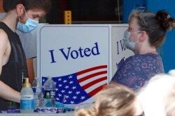 A voter fills out his ballot as a woman waits her turn during primary voting at the public safety building in McKeesport, Pa., Tuesday, June 2, 2020. (AP Photo/Gene J. Puskar)