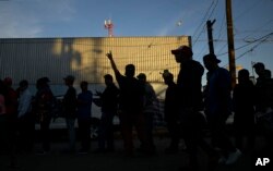 Men line up for dinner outside a shelter housing members of the migrant caravan, in Tijuana, Mexico, Nov. 26, 2018.