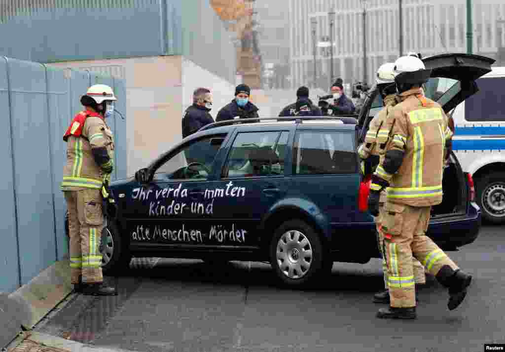 Firefighters remove the car that crashed into the gate of the main entrance of the office of German Chancellor Angela Merkel in Berlin.