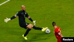 Gadyen ameriken Tim Howard k ap bloke yon balon bèlj Kevin Mirallas shoute nan match 8èm de final ant Beljik/Etazini nan vil Salvador, Brezil (1er jiyè, 2014.)