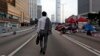 A man walks to work as the pro-democracy student protesters sleep on a roadside in the occupied areas surrounding the government complex in Hong Kong, Oct. 6, 2014. 