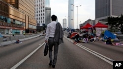 A man walks to work as the pro-democracy student protesters sleep on a roadside in the occupied areas surrounding the government complex in Hong Kong, Oct. 6, 2014. (AP Photo/Kin Cheung) 