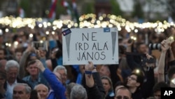 Demonstrators hold a placard reading "Don't sign it, Janos" referring to President Janos Ader as they protest against the amendment of the higher education law seen by many as an action aiming at the closure of the Central European University, founded by Hungarian born American billionaire businessman George Soros, in front of the Parliament building in Budapest, Hungary, April 9, 2017.