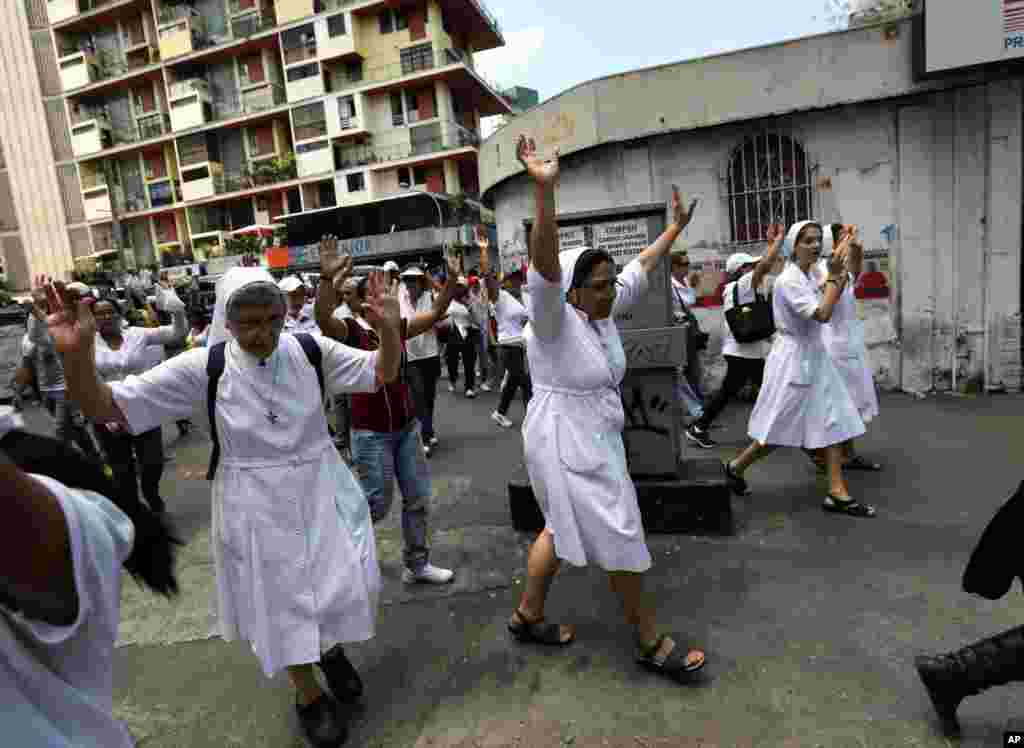 Nuns raise their arms during a women&#39;s march protesting repression against anti-government demonstrators in Caracas, Feb. 26, 2014. 