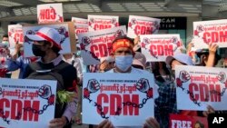 Anti-coup protesters hold posters with "CDM," initials that stand for Civil Disobedience Movement, as they gather outside the Hledan Centre in Yangon, Myanmar, Sunday, Feb. 14, 2021. Daily mass street demonstrations in Myanmar are on their second week, with neither protesters nor