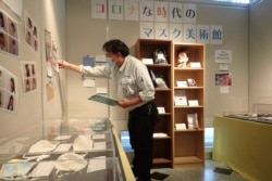 In this photo provided by curator Makoto Mochida of the Historical Museum of Urahoro, Mochida examines the newspaper clips and other items he is collecting to document how life was affected by the coronavirus pandemic at the museum.