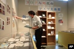 In this photo provided by curator Makoto Mochida of the Historical Museum of Urahoro, Mochida examines the newspaper clips and other items he is collecting to document how life was affected by the coronavirus pandemic at the museum.