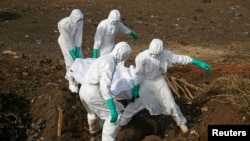 FILE - Health workers carry the body of a suspected Ebola victim for burial at a cemetery in Freetown, Sierra Leone, Dec. 21, 2014.