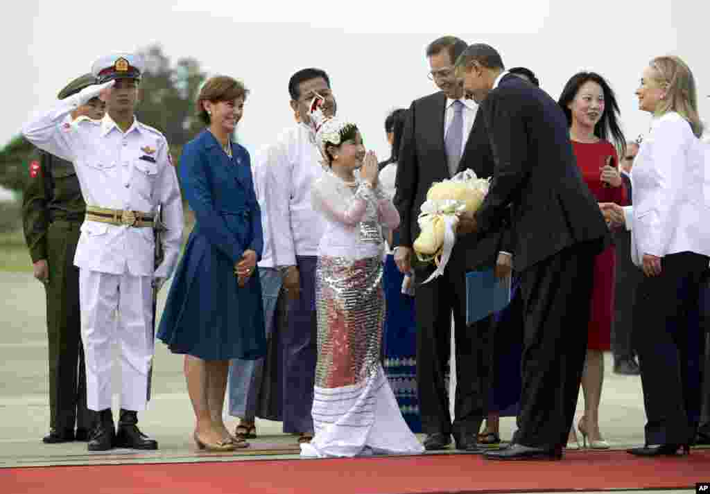 US President Barack Obama is presented with flowers as he and Secretary of State Hillary Rodham Clinton, right, arrive at Rangoon International Airport in Burma, Nov 19, 2012. 