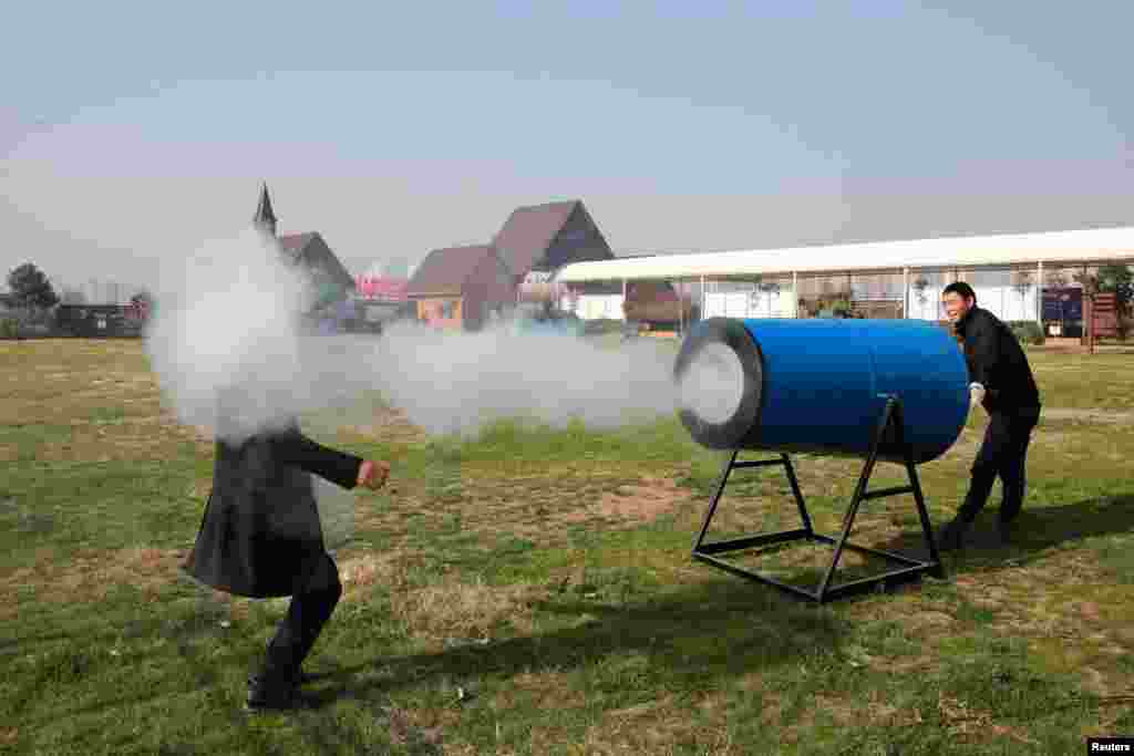 Dua orang pria mendemonstrasikan meriam asap buatan, yang dapat menyemburkan asap yang terbuat dari &quot;air dan noda tembakau&quot;, untuk mengingatkan masyarakat pentingnya menjaga lingkungan di Xiangyang, provinsi Hubei, China.