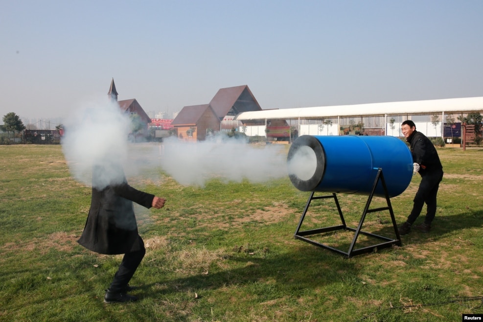 People demonstrate a home-made "smog cannon" which fires cannonballs made of "water and tobacco tar" to remind people the importance of protecting environment, in Xiangyang, Hubei province, Dec. 27, 2016. 