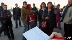 Belarusians check their numbers in the line to buy a foreign currency outside an exchange booth in Minsk, Belarus, Wednesday, May 25, 2011