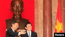 China's State Councillor Yang Jiechi, left, stands with Vietnam's President Truong Tan Sang in front of a bust of the late Vietnamese revolutionary leader Ho Chi Minh, at the Presidential Palace in Hanoi, Oct. 27, 2014.