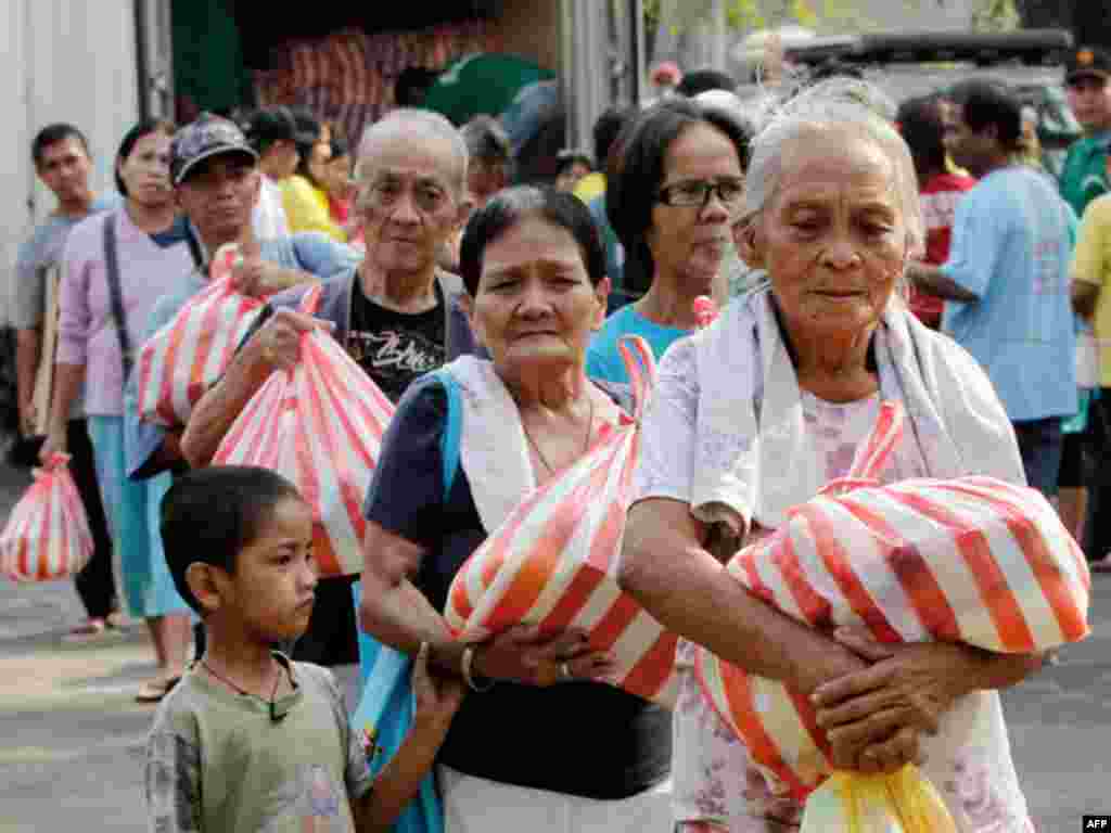 Residents hold on to grocery hand outs during a Christmas give-away event in Manila December 23, 2010.