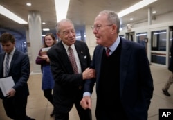 Senate Judiciary Committee Chairman Chuck Grassley, R-Iowa, left, grabs Sen. Lamar Alexander, R-Tenn., chairman of the Senate Health, Education, Labor, and Pensions Committee, right, as they and other lawmakers rush to the chamber to vote on amendments to the Republicans' tax bill, on Capitol Hill in Washington, Nov. 30, 2017.