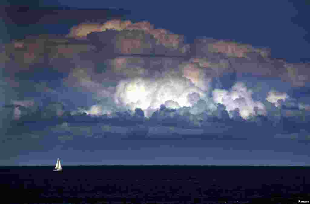 A storm cloud can be seen behind a yacht as it sails off the coast of Sydney, Australia, Mar. 31, 2014. The Bureau of Meteorology last week forecast 'warmer and drier than usual' weather extending into winter for Sydney and most of south-eastern Australia over the next three months.