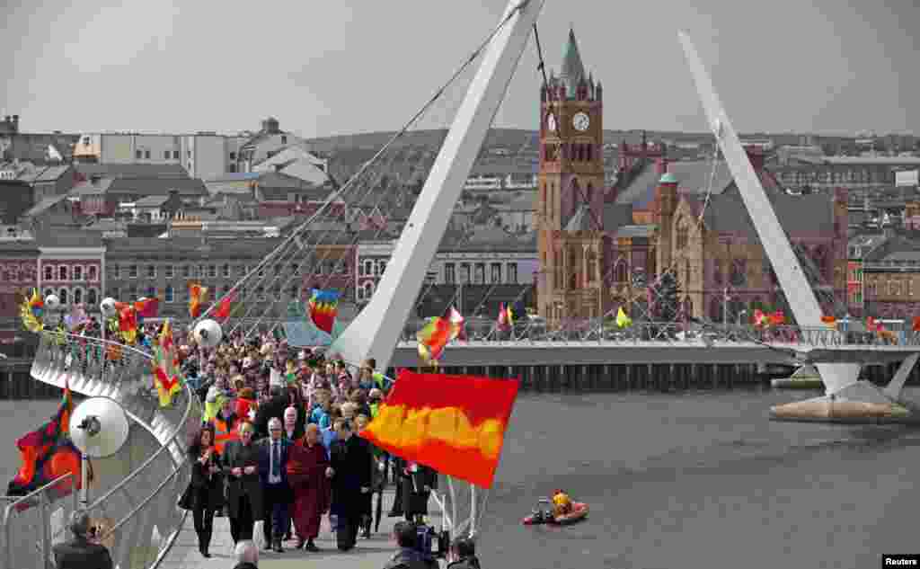 Tibetan spiritual leader the Dalai Lama walks across the Peace Bridge during his visit to Londonderry, northern Ireland. 