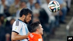 Argentina's Ezequiel Garay, left, and Netherlands' Robin van Persie go for a header during their World Cup semifinal soccer match at Itaquerao Stadium in Sao Paulo, July 9, 2014.