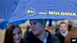 Moldovan students hold an umbrella that uses the European Union symbol to form the sentence "I am Moldova" after arriving in the Romanian capital to vote, at the main railway station, Gara de Nord, in Bucharest, Romania, Sunday, Nov. 30, 2014. Moldovans 