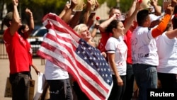 FILE - Anti-deportation protesters chant in front of the White House in Washington in August. U.S. President Barack Obama signed two executive orders reforming immigration policies on Nov. 21, 2014.