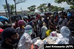 Sejumlah pengendara motor menjalani tes usap (swab) COVID-19 di pos pemeriksaan di Surabay, Minggu, 6 Juni 2021. (Foto: Juni Kriswanto/AFP)