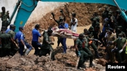 Anggota militer Sri Lanka mengangkut jenazah korban tewas akibat tertimbun sampah longsor di pinggiran Kolombo, Sri Lanka, Minggu (16/4). 