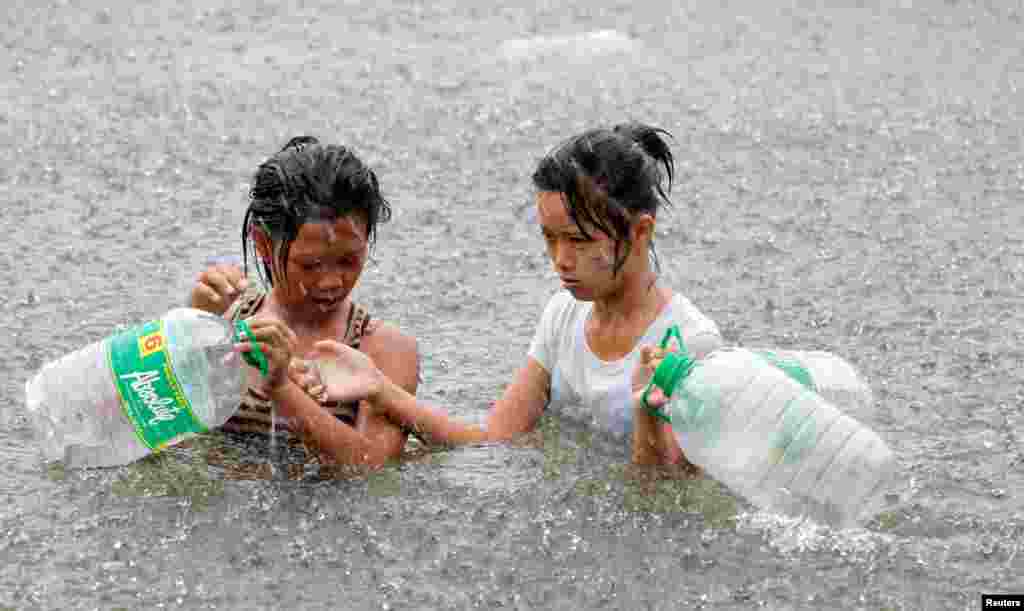 Warga mengarungi jalanan yang terendam banjir untuk membeli air minum di Malabon, Manila (1/8).