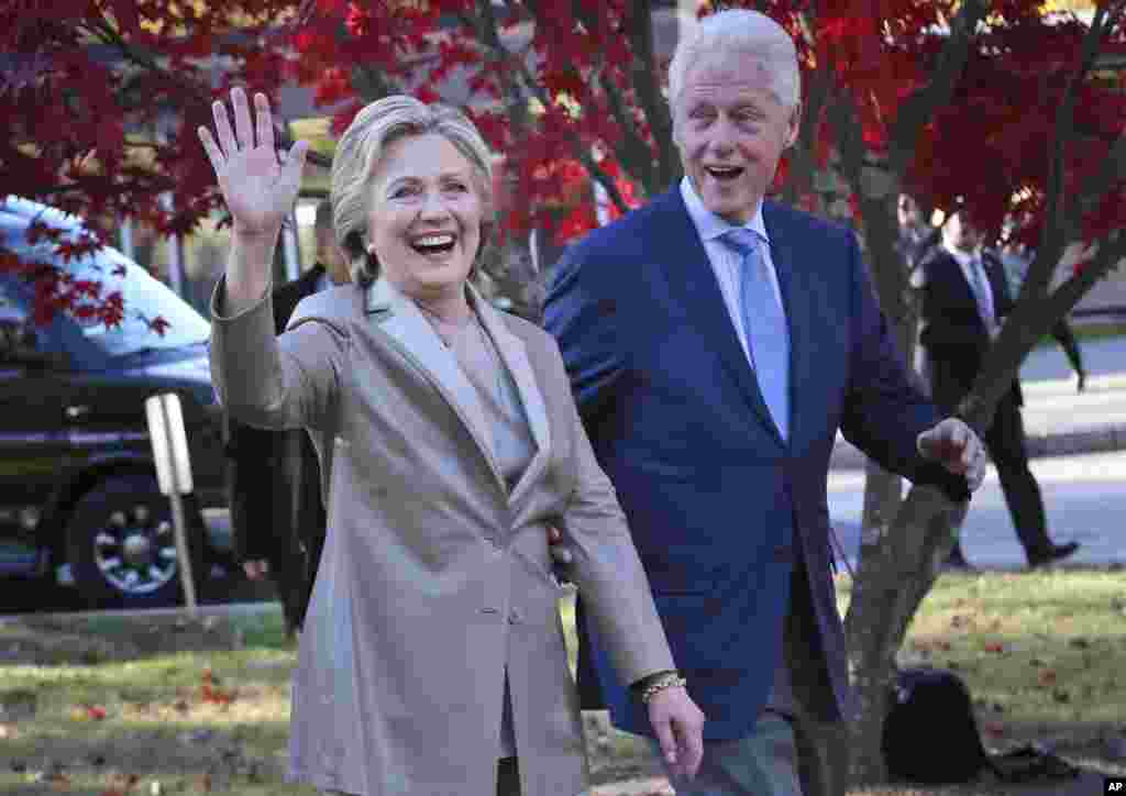 Kandidat presiden dari Partai Demokrat, Hillary Clinton, dan suaminya Bill, menyapa warga setelah memberikan suara di TPS di Chappaqua, New York (8/11). (AP/Seth Wenig)